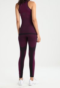 Top atlético ajustado y leggins en burdeos oscuro con un patrón texturizado, con detalles en negro y un diseño elegante.