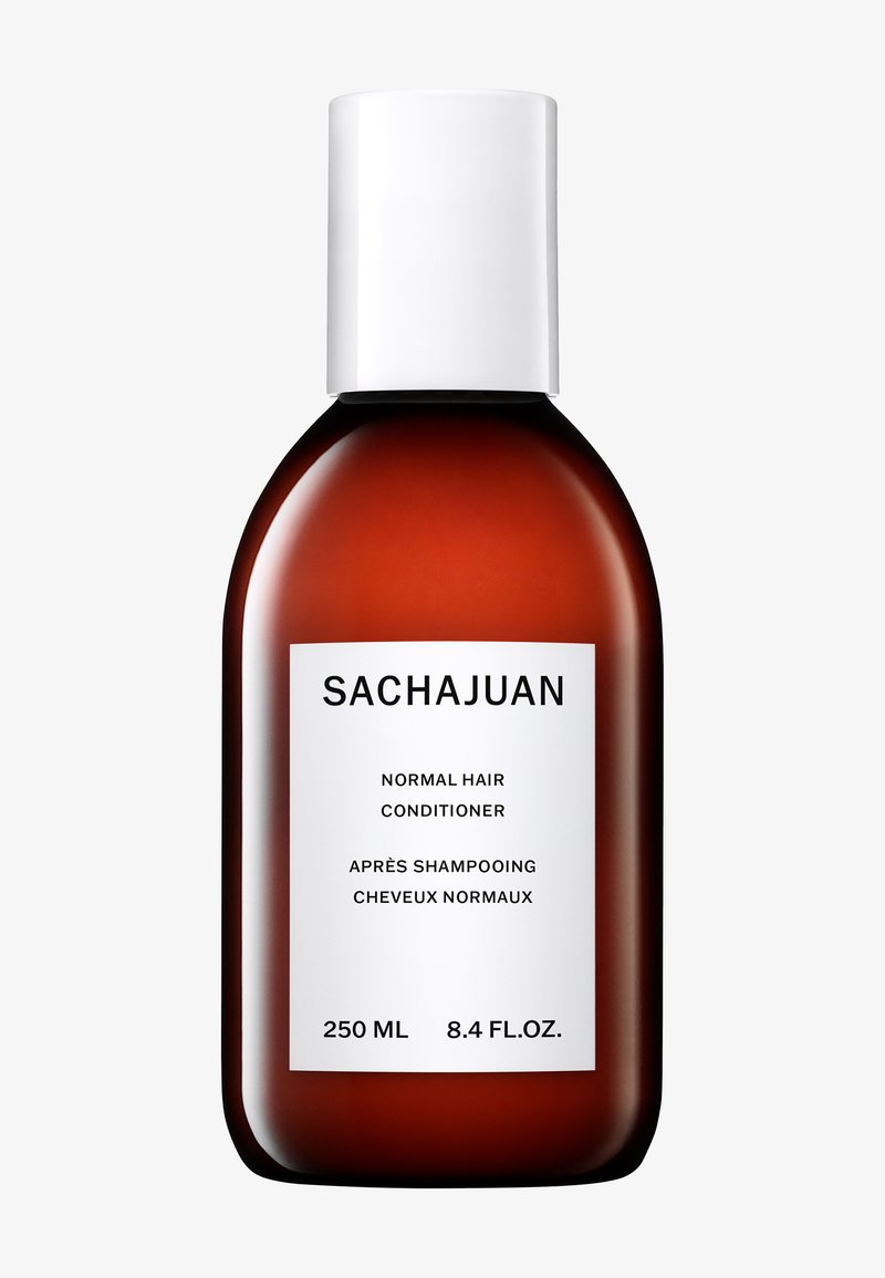 Klar flaske av amberglass med en hvit pumpehette. Etiketten sier "Sachajuan Normal Hair Conditioner," med spesifikasjoner på 250 ml og 8,4 fl oz.