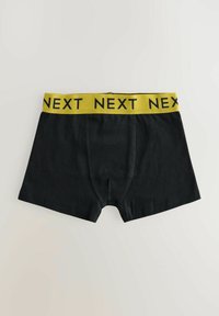 Crne bokserice s žutom elastikom na struku na kojoj se ponavlja riječ "NEXT". Tkanina izgleda glatko i rastezljivo.
