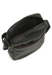 Bolso cruzado de cuero negro con costuras rojas, compartimentos con cremallera, correa ajustable y textura suave. Bolsillo interior visible.