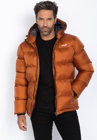 Giacca outdoor arancione imbottita con cappuccio, caratterizzata da un design trapuntato, zip frontale e una fodera interna nera. Logo del marchio sul petto.