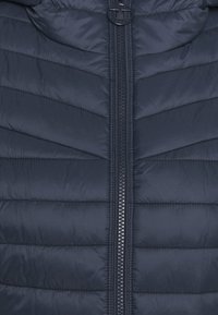 Navy blue padded jacket with chevron quilted design, featuring a central nylon zipper and a round zipper pull, soft texture.