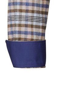 Polsino di camicia a quadri nei colori azzurro chiaro, marrone e crema, con un rivestimento in tessuto blu navy solido. Presenta un motivo a tartan e un design sartoriale.