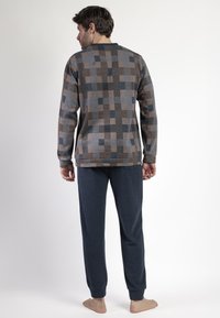 Conjunto de ropa de estar para hombres que incluye una camiseta de manga larga con un diseño en tonos marrones y azules, combinada con pantalones rectos de color azul marino. Textura suave.