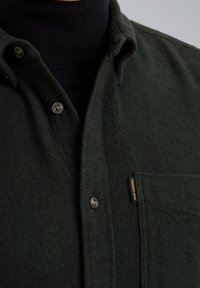 Tmavě zelená flanelová košile s límcem na knoflíky, náprsní kapsou a kovovými knoflíky, s etiketou označenou "PME LEGEND" na kapse.