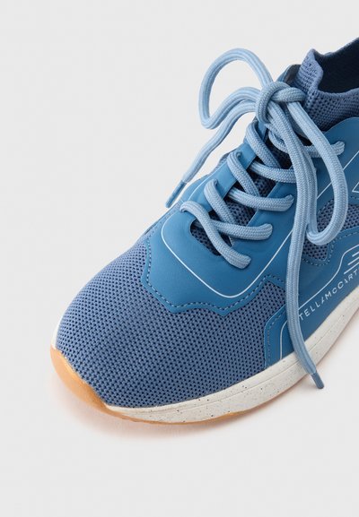 Modrá sportovní obuv s mesh svrškem, texturovanými překrytími a plochými tkaničkami. Má polstrovanou podrážku se skvrnitou mezipodešví a gumovou podešví.