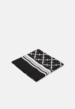 Tissu noir et blanc plié avec un motif géométrique en forme de trèfle et deux bandes blanches parallèles sur un fond uni.