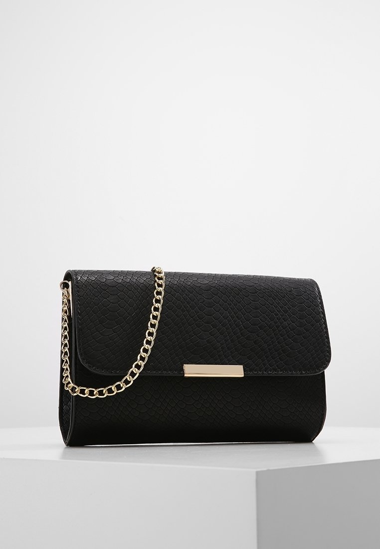 Černá kabelka z umělé kůže s texturovaným povrchem, zlatým řetízkovým popruhem, magnetickým uzávěrem na klopu a obdélníkovým zlatým akcentem na přední straně.