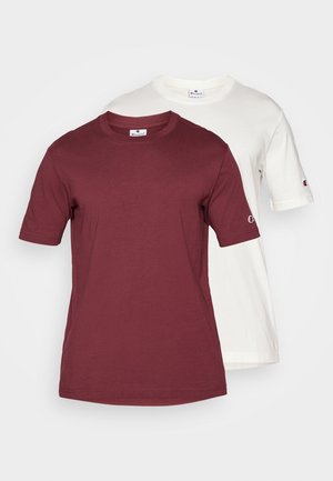 Two short-sleeve T-shirts stacked; one maroon and one white. Both are made of cotton, featuring a round neck and logo on the sleeve.