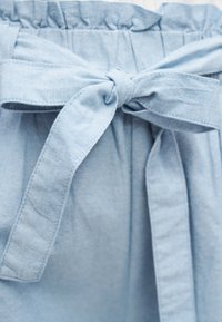 Ανοιχτό γαλάζιο ύφασμα δεμένο σε μια τακτοποιημένη φιόγκο με ορατή ραφή, μαζεμένο στην πάνω άκρη που προτείνει ζώνη ή ένδυμα λεπτομέρεια.