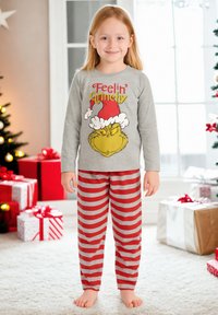 Maglietta grigia a maniche lunghe con il testo "Feelin' Grinchy" e una grafica del Grinch abbinata a pantaloni da pigiama a righe rosse e grigie.