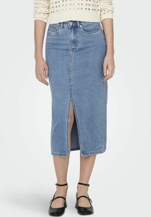Lyseblå cowboy nederdel til knæet med frontslids, båret med cremefarvet sweater og sorte ankelremssko, vist fra talje til fødder.