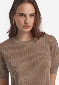 Strickpullover in Taubengrau mit kurzen Ärmeln, der eine gerippte Struktur und einen runden Ausschnitt aufweist. Glatter Stoff mit weichem Finish.