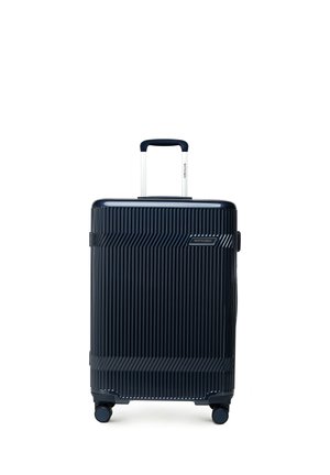 Dunkelblauer Hartschalenkoffer mit vertikalen Rillen, Teleskopgriff und vier drehbaren Rädern, aufrecht stehend vor weißem Hintergrund.