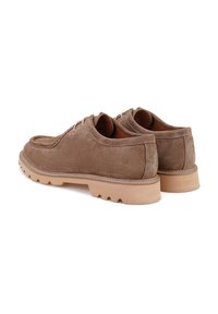 Bruine suède schoenen met een gladde textuur, uitgerust met een ronde neus, vetersluiting en een robuuste rubberen zool voor grip.