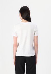 Witte katoenen T-shirt met een ronde halslijn en korte mouwen, voorzien van een relaxte pasvorm. De stof lijkt glad en licht van gewicht.