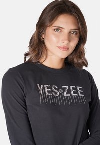 Maglietta nera a maniche lunghe in cotone, con grafica 'YES&ZEE' in strass, dotata di un collo rotondo e design aderente.