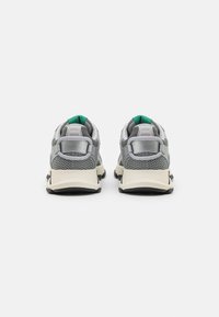 Gray athletic shoes with mesh and synthetic material, featuring a rounded toe, black sole, and green accents on the heel tab.