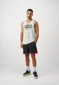 Valge võrgust tank top, millel on tekst "UNDER ARMOUR BASKETBALL", rohelised aktsendid. Mustad lühikesed püksid roosa äärisega. Mustad ja rohelised spordijalatsid.
