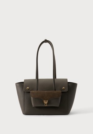 Sac cabas en cuir marron foncé avec poche à rabat présentant un détail en daim et un fermoir doré, deux longues anses sur fond neutre.