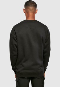 Schwarzer Sweatshirt mit runder Halslinie und abgesenkten Schultern, aus weichem Stoff mit glatter Textur und Rippbündchen.