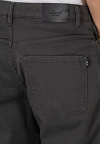Dark gray denim pants featuring a back patch pocket and leather brand label. The fabric has a smooth texture with a classic five-pocket design.