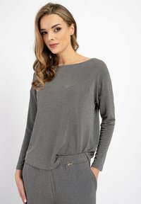 Szara longsleeve z luźnym krojem i strukturalnym materiałem. Okrąg�ły dekolt i obniżone ramiona. Połączona z pasującymi spodniami na sznurki.
