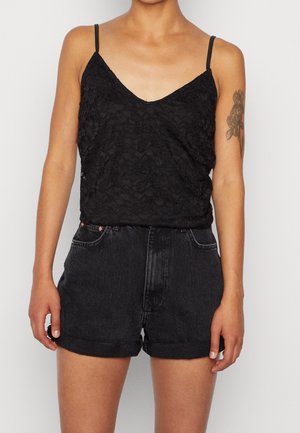 Sort blonde camisole med tynde stropper og V-udskæring, kombineret med sort, højtaljet denimshorts med opbuk og forlommer.