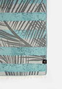 Gewoven dekentje met een blauw en grijs gestreept patroon, waarin palmenbladdesigns zijn verwerkt. De randen hebben een franjerand en een klein zwart label.