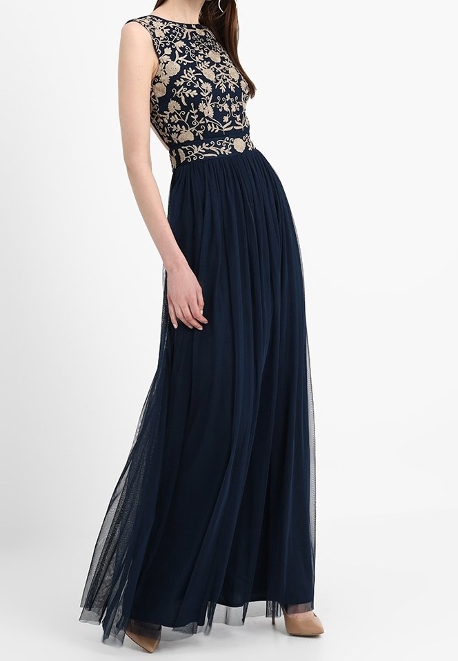 Mörkblå kvällsklänning med ärmlös, broderad bodice med blommönster och en flödande, genomskinlig kjol. Slät tyg med utsvängd design.