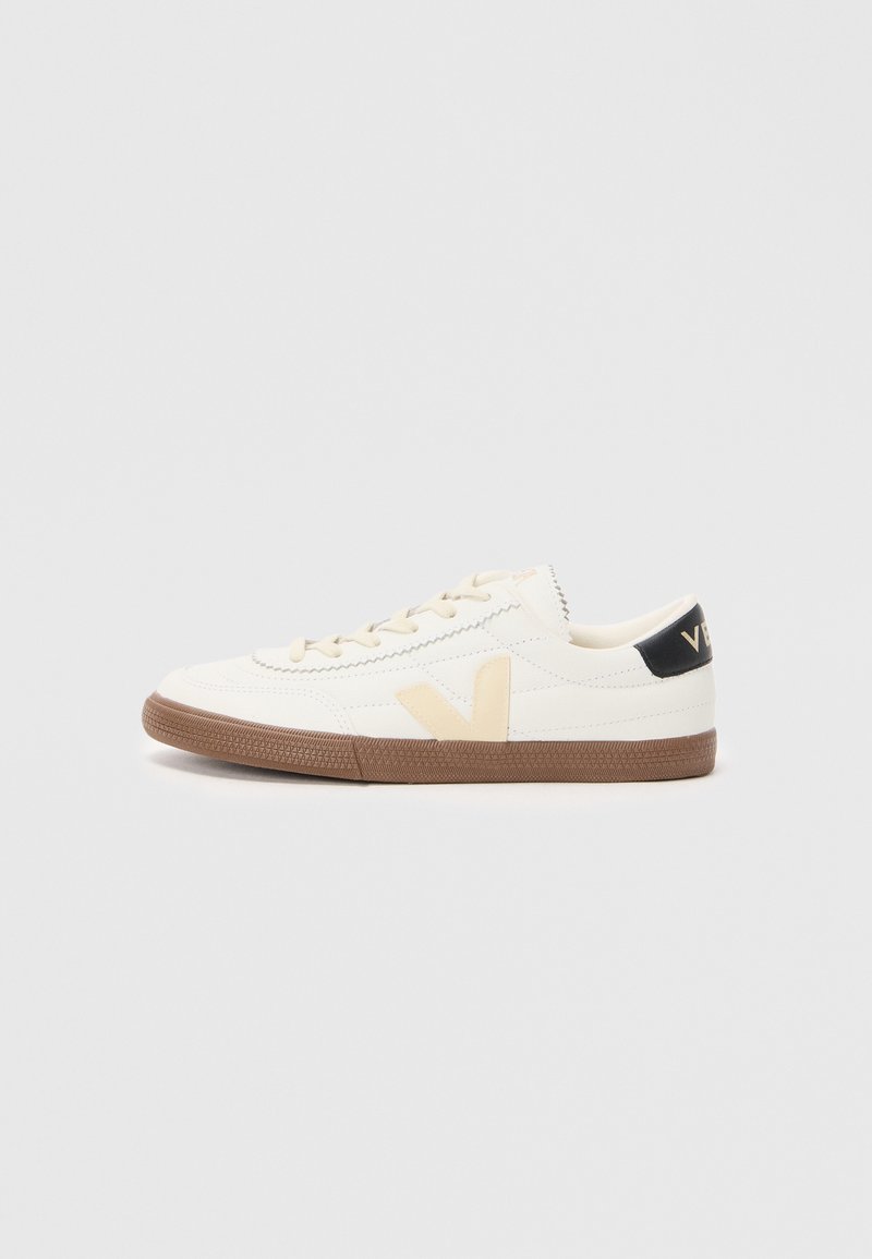 Λευκό αθλητικό παπούτσι από λείο συνθετικό υλικό, με λογότυπο V σε μπεζ απόχρωση, ανοιχτό καφέ ελαστική σόλα και μαύρες λεπτομέρειες στη φτέρνα.