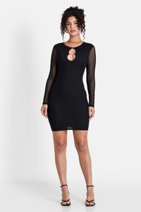 Schwarzes Kleid mit langen, transparenten Ärmeln, das ein Schlüssel-Ausschnitt-Detail aufweist. Figurbetontes Design, bis zur Mitte der Oberschenkel reichend, kombiniert mit schwarzen Riemchen-Heels.