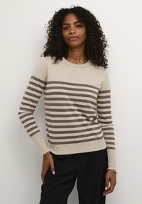 Maglione beige con strisce orizzontali marroni scure. Collo rotondo, maniche lunghe, polsini e orlo a coste. Materiale morbido con vestibilità rilassata.