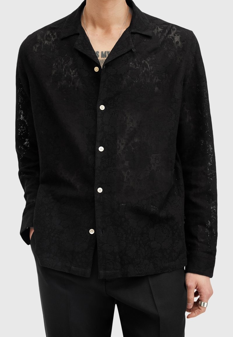 Camicia nera a maniche corte con motivo floreale testurizzato, colletto e bottoni bianchi, realizzata in tessuto leggero.