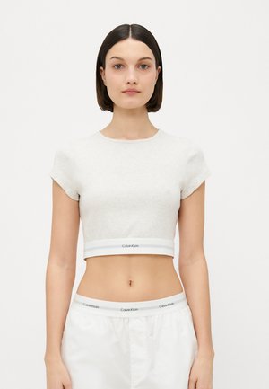 Top court gris clair en tissu texturé. Présente une bande blanche à l'ourlet avec le logo "Calvin Klein". Manches courtes, design ajusté.
