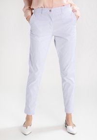 Ljusblå randiga byxor med slim fit, tillverkade av ett mjukt tyg. Har sidofickor och knäppning med knapp. Matcher med vita skor.