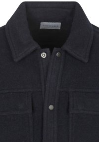 Donkerblauwe wollencoat met een kraag, drukknoopjes en twee borstzakken met kleppen, waarbij het bovenste voorste gedeelte zichtbaar is.