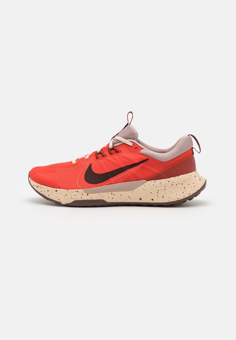Scarpe da ginnastica atletiche rosse con tomaia in tessuto texturizzato, logo Nike marrone e suola beige maculata. Presentano chiusura con lacci e linguetta sul tallone.