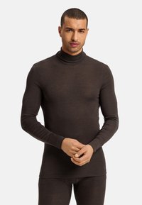 Brązowy sweter z długim rękawem, wykonany z delikatnej tkaniny, o dopasowanym kroju, z wysokim kołnierzem i bezszwowym wykończeniem mankietów, w komplecie z dopasowanymi spodniami.