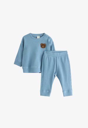 Blå bomullstvådelad outfit med ribbat mönster, långärmad topp med en björnpatch och byxor med elastisk midja.