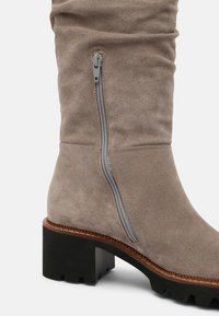 Bota de ante topo de media caña con cremallera lateral, costuras de welt marrón y tacón cuadrado negro y grueso con suela con relieve.