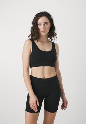 Zwarte sportbeha en hoge shorts. Gemaakt van een gladde stof met een aansluitend ontwerp. Beschikt over brede banden en een minimalistische stijl.