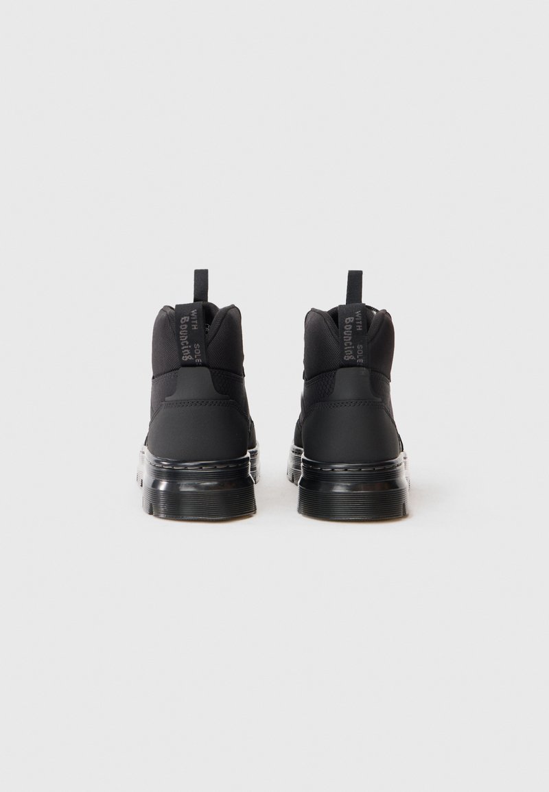 Black ankle boots made of synthetic material, featuring a smooth texture, rounded toe, and contrasting rubber sole with branding on the heel.