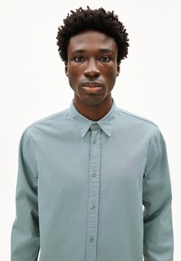 Lichtblauw button-up overhemd met een kraagontwerp, voorzien van een slim fit, een gladde textuur en een klein geborduurd logo op de borst.
