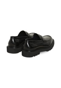 Mocassins noirs en cuir à enfiler avec semelles épaisses et rainurées, vus de dos sur fond blanc.