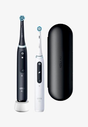 Zwei elektrische Zahnbürsten, eine schwarze auf einer Ladestation und eine weiße, neben einem schwarzen Reiseetui, alle Oral-B iO Modelle.