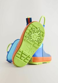 Blaue Gummiregenstiefel mit grüner Sohle, orangefarbener Texturbande und mehrfarbigen Ziehlaschen. Die Sohle weist verspielte Designmuster auf.