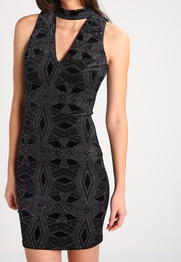 Robe noire mini avec un décolleté en V profond, détail de tour de cou et motifs géométriques en paillettes argentées. Silhouette ajustée, design sans manches.