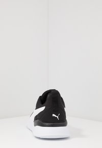 Black and white athletic shoes featuring a textured upper, padded collar, pull tab, and a white logo on the heel. Lightweight design.