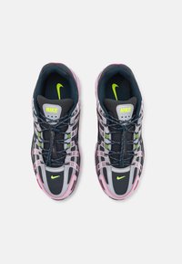 Des baskets Nike avec une tige en maille noir et gris foncé, des accents en caoutchouc rose, des détails vert lime et un design à lacets avec des boutons de réglage.